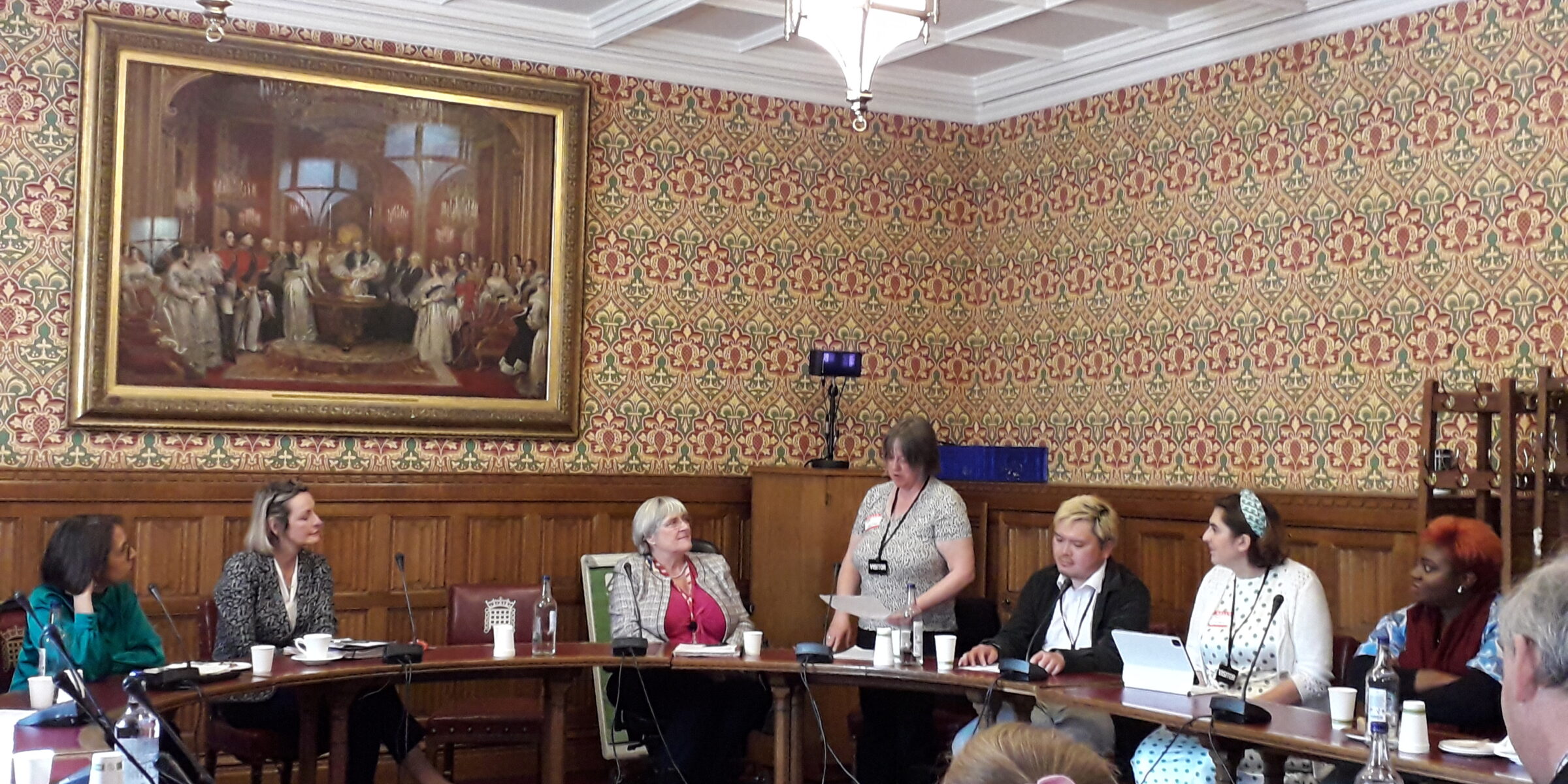 Patsy is standing in the House of Lords talking about her life in a room full of people.